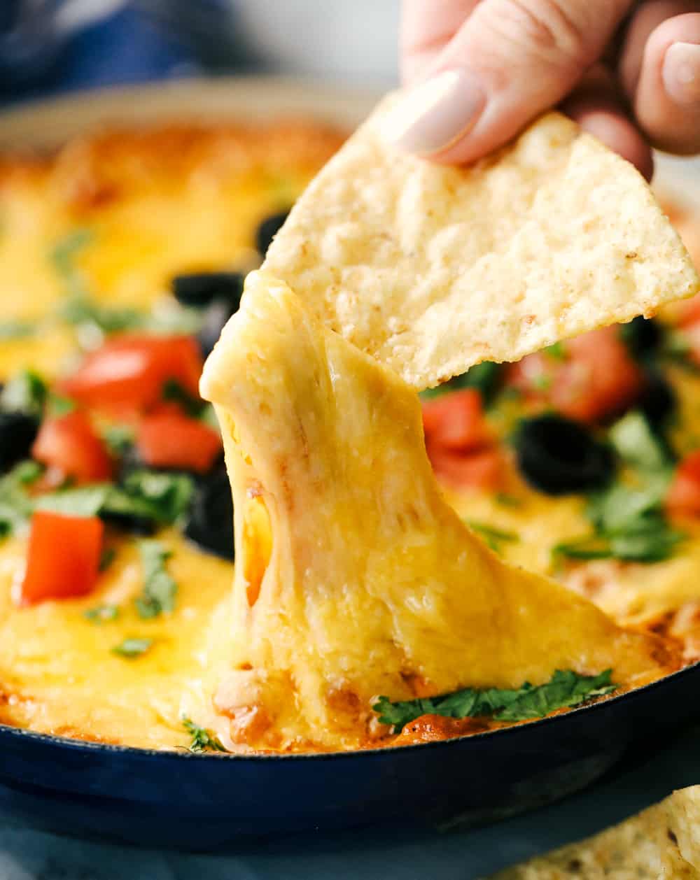 Bean dip with a chip dipping into the dip.