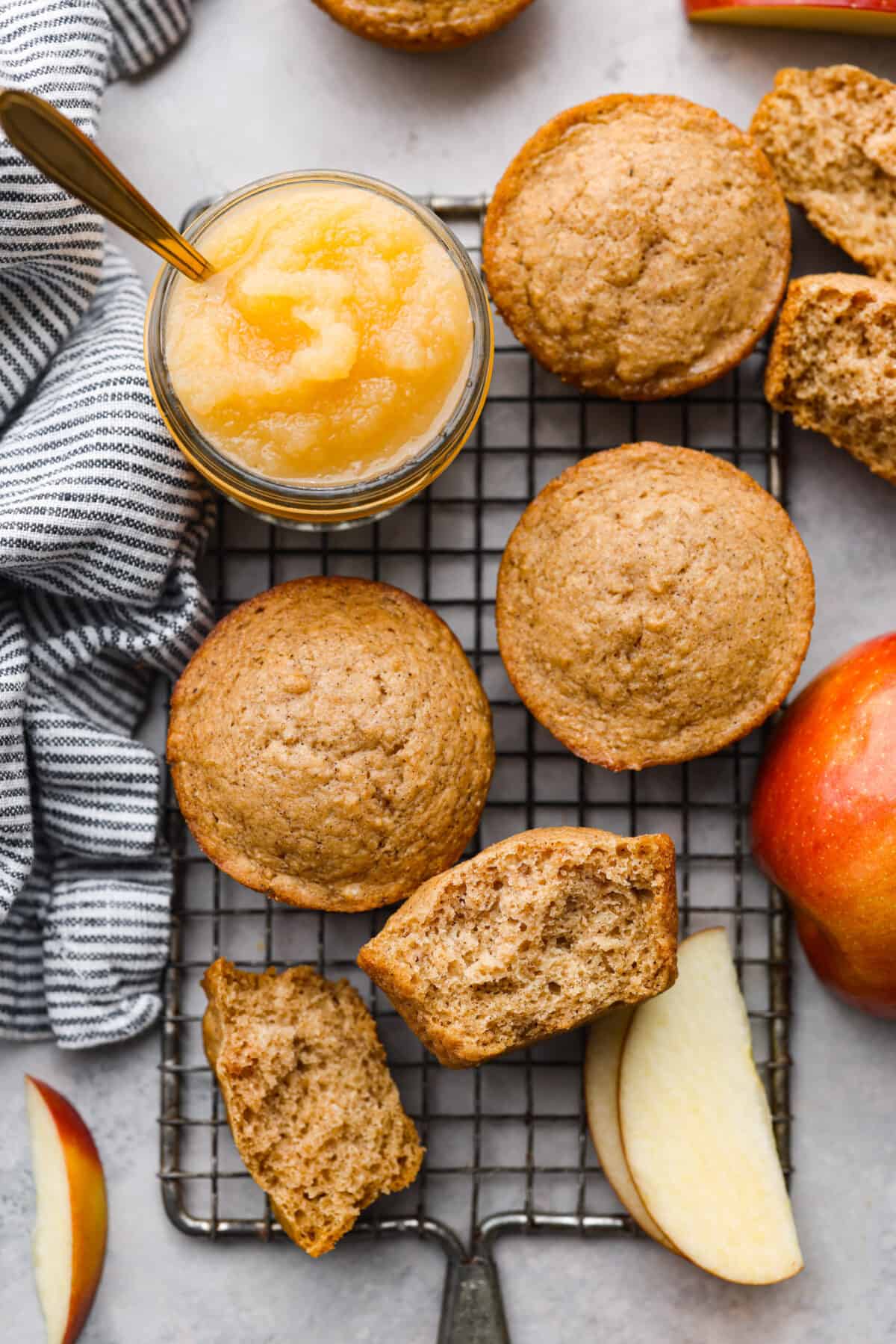 Top-down view of applesauce muffins on a wire rack. One is torn in half.