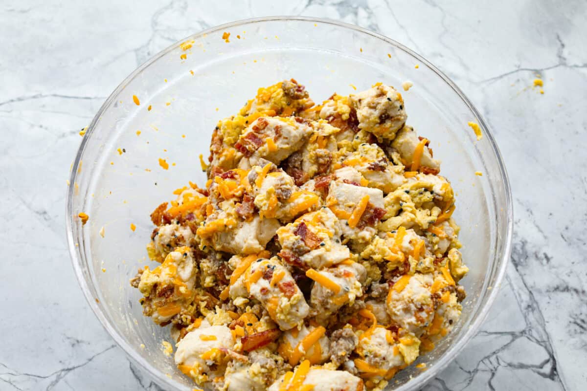 Overhead shot of breakfast monkey bread ingredients stirred together in a bowl. 