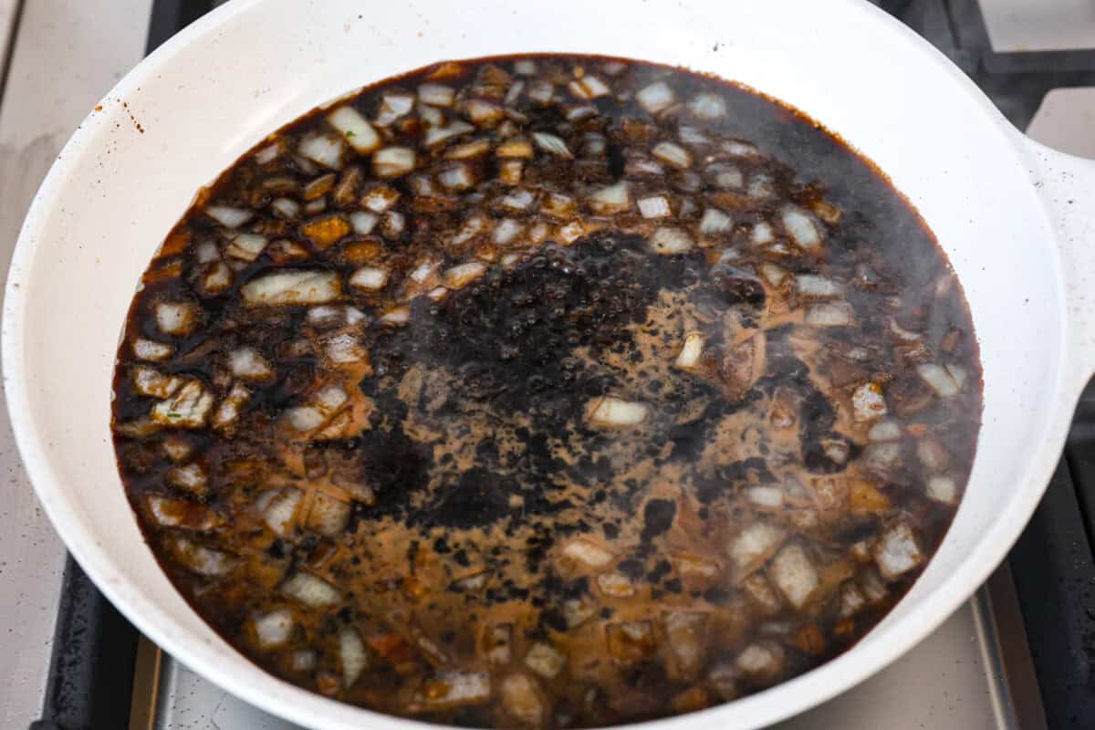 Angle shot of sauce and onions boiling in the skillet. 