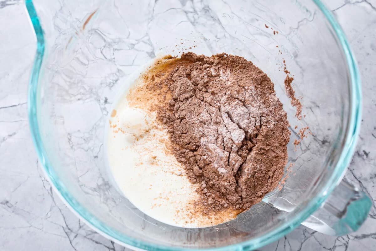 Overhead shot of dry ingredients with cream in a glass bowl. 