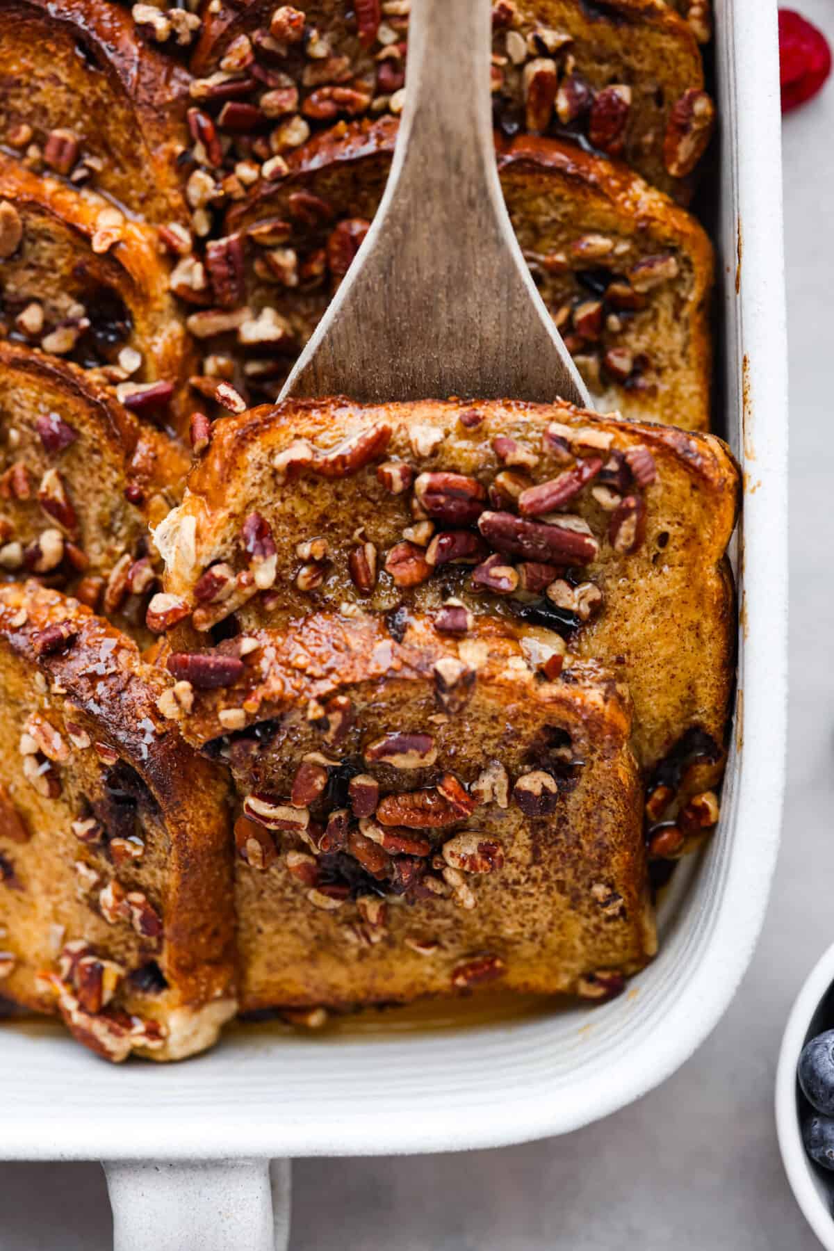 Serving a slice of French toast with a wooden spatula.