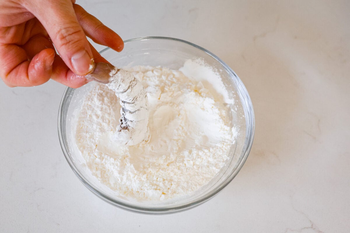 Coating a piece of shrimp in flour.