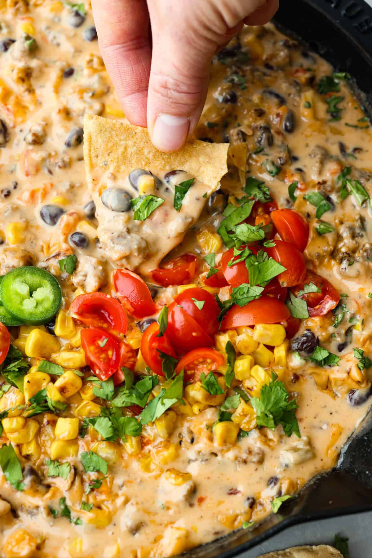 A chip being dipped in cowboy queso. 