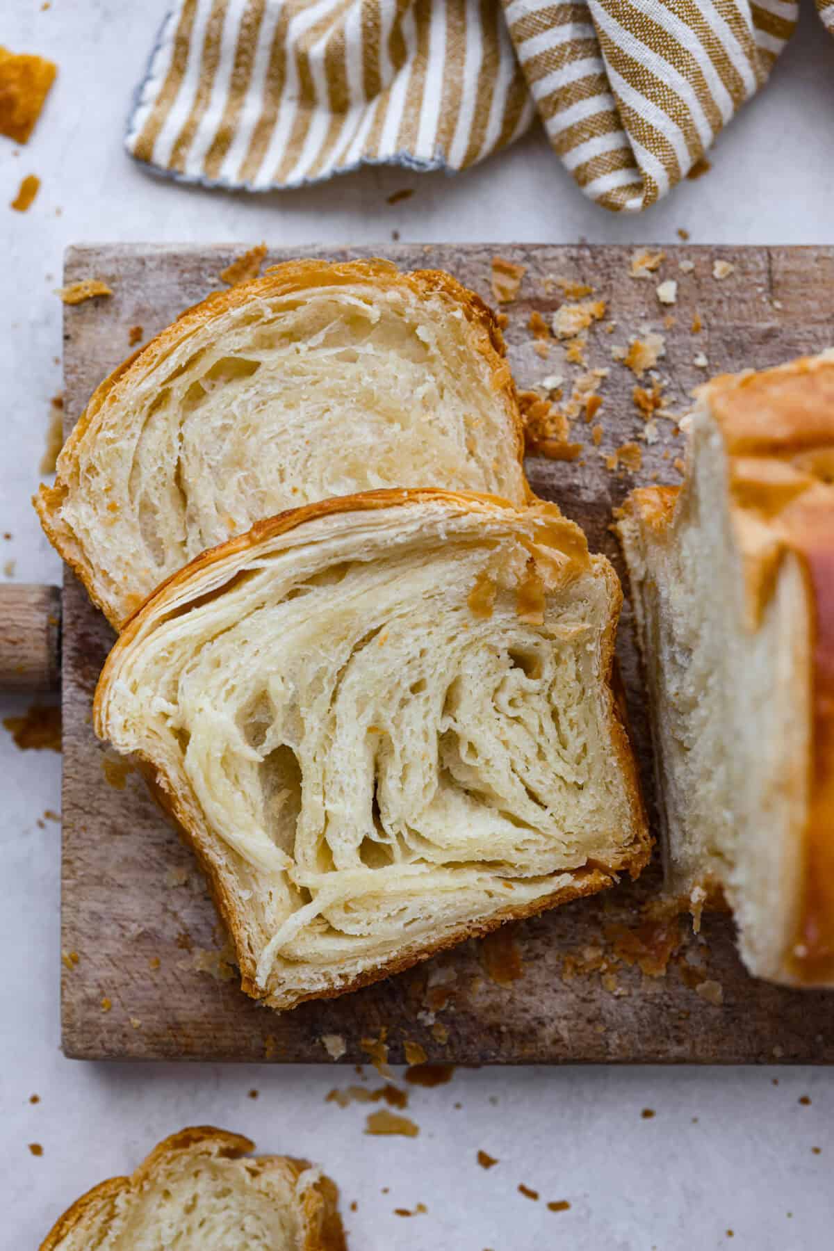 Overhead shot of slices of croissant bread on cutting board. 