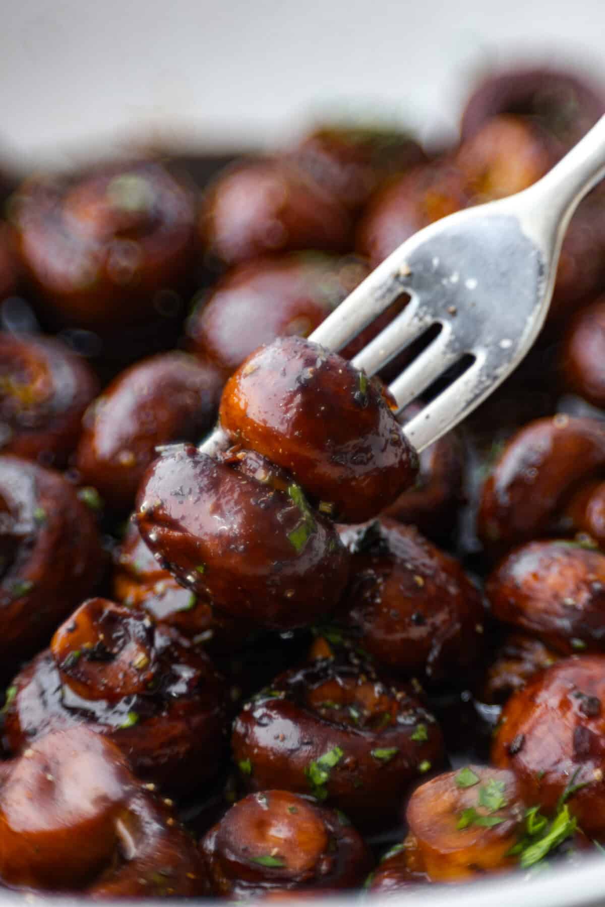 Close view of a fork poking mushrooms from the skillet.