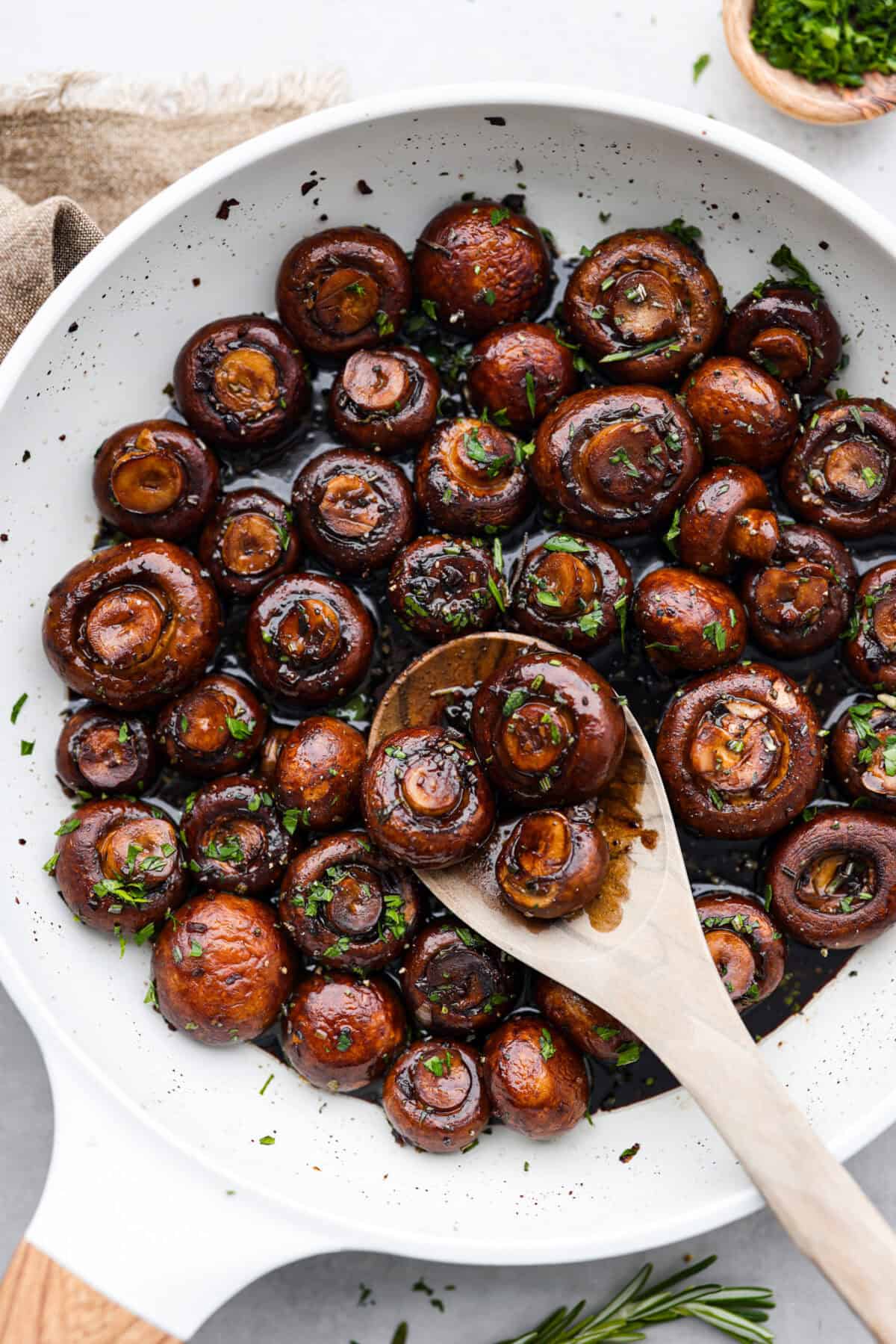 Top view of garlic balsamic mushrooms in a skillet with a wood serving spoon.