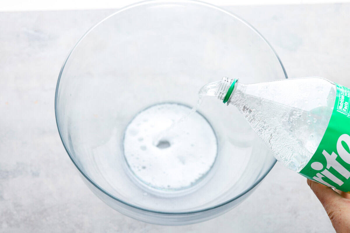 Overhead shot of sprite being poured into a large bowl.