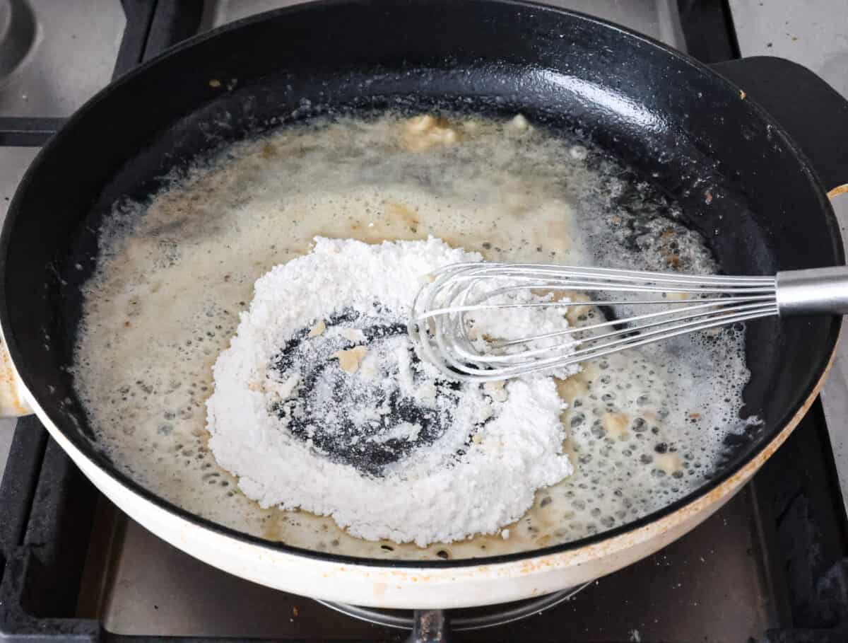 Overhead shot of flour being whisked into butter at the bottom of skillet. 