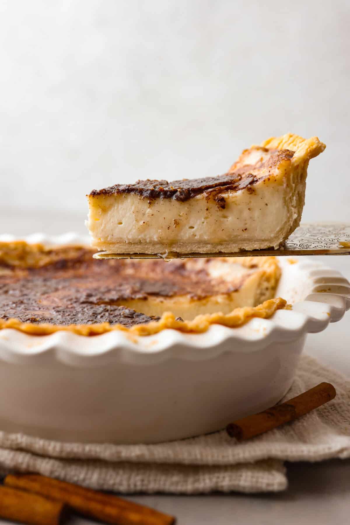 Side shot slice of sugar cream pie being lifted from pie pan. 