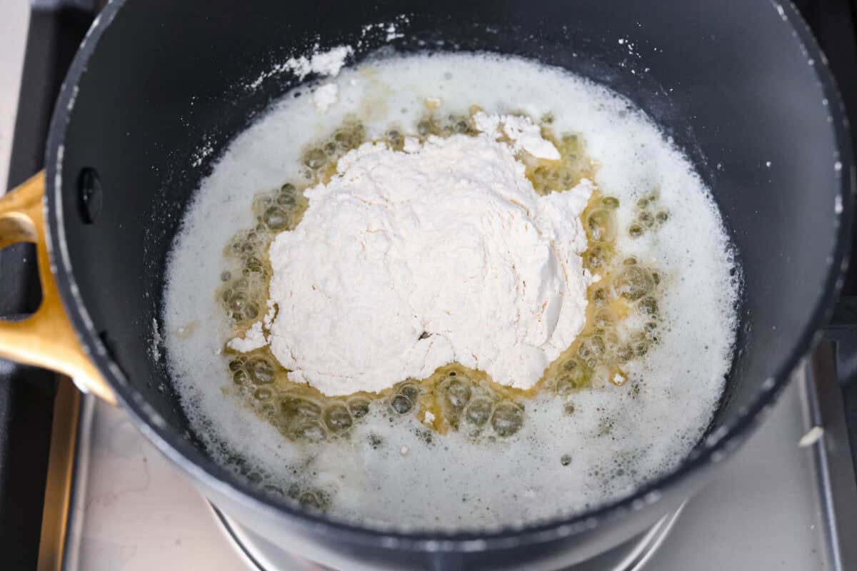 Overhead shot of melted butter in the bottom of a pot with flour on top.