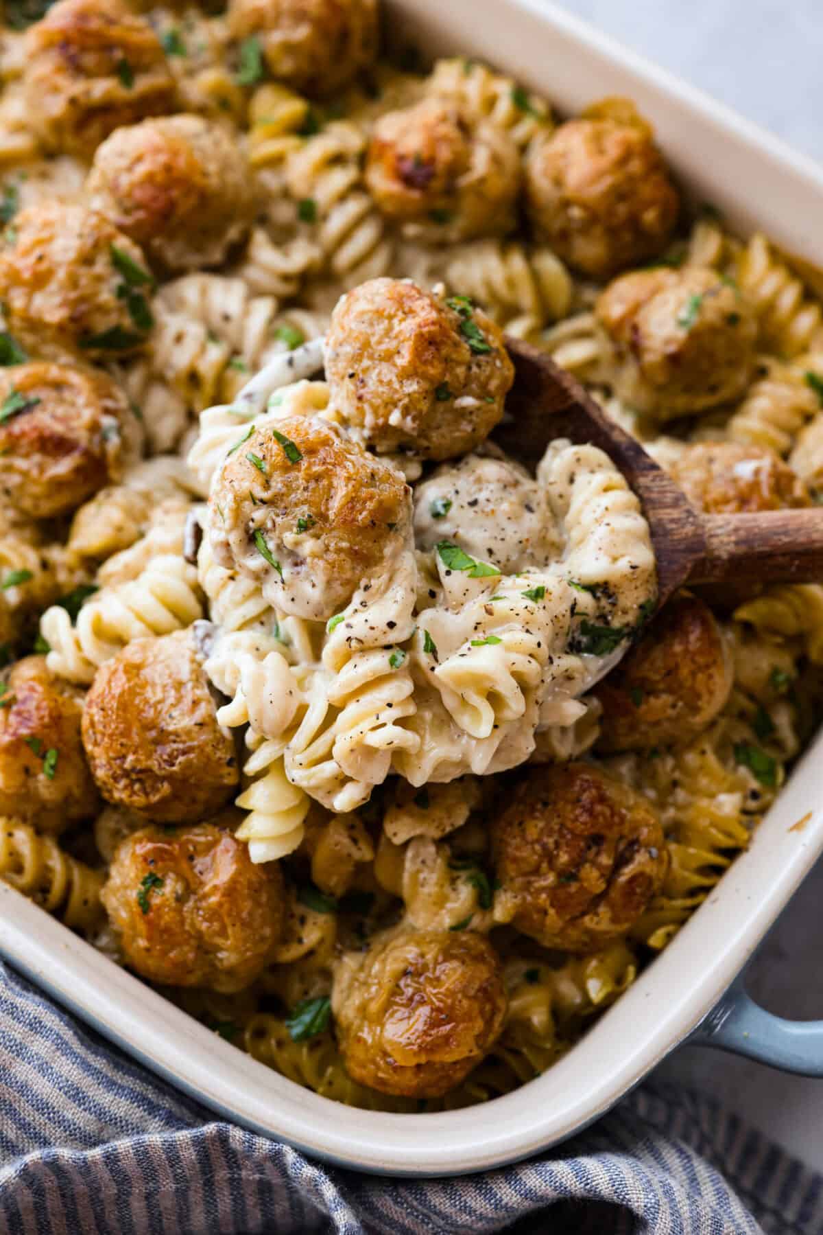 Close up shot of a wooden spoon with a scoop of Swedish meatball casserole. 