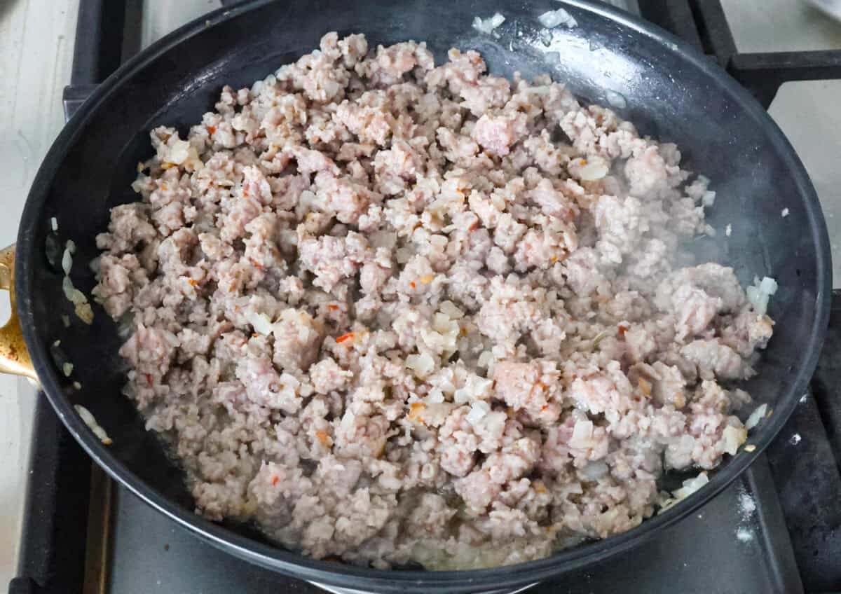 Angle shot of Italian sausage being cooked on the stove top. 