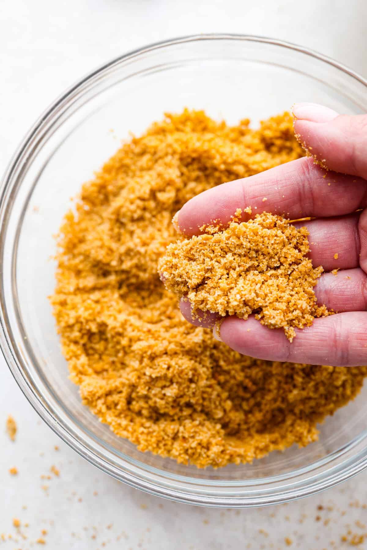 Overhead shot of someone holding a handful of the crust mixture. 