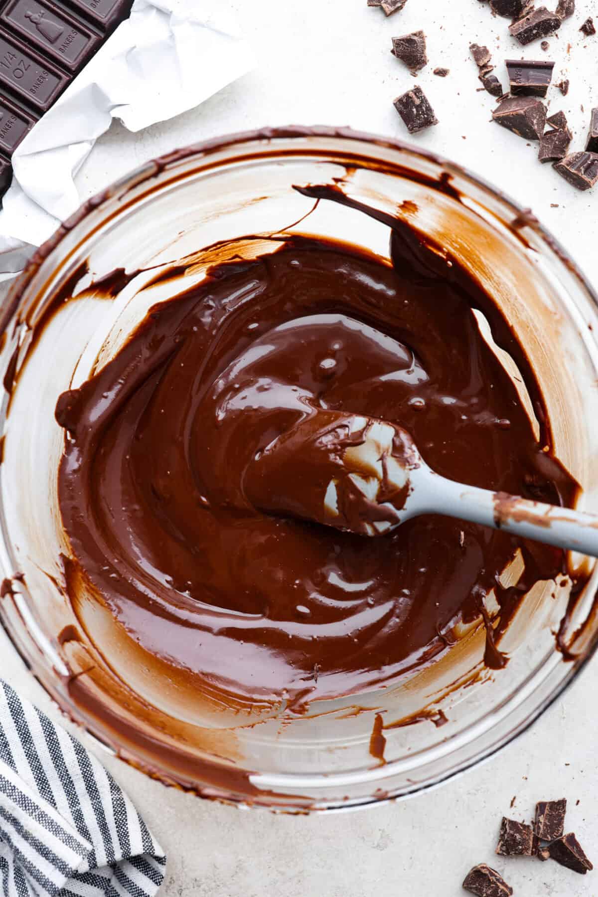 Top view of tempered chocolate in a glass bowl with a spatula.