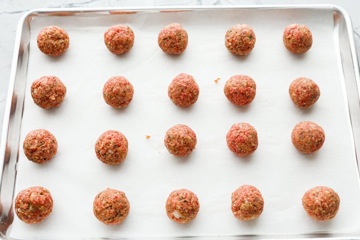 Fourth photo of the mozzarella stuffed meatballs placed on a baking sheet to bake.