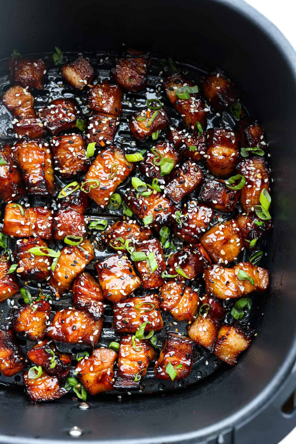 Overhead shot of air fryer pork belly bites covered in marinade. 