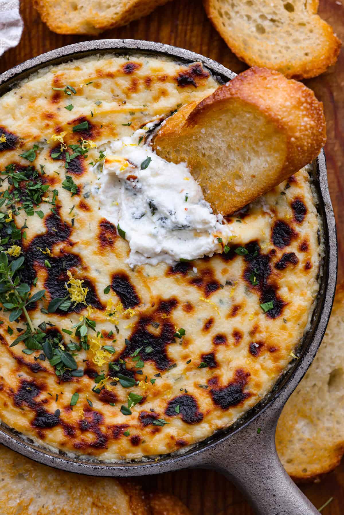 Close up shot of baked ricotta dip with crostini. 