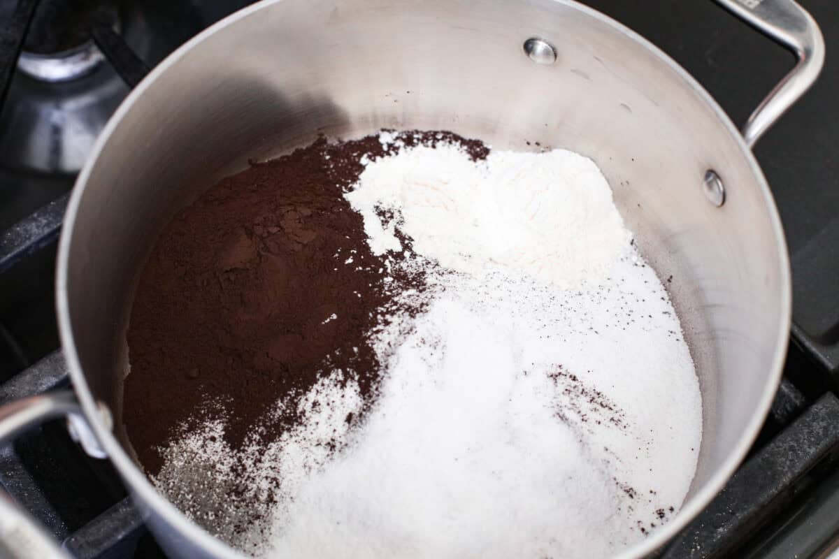 Overhead shot of sugar, black cocoa powder, and flour in a pan. 