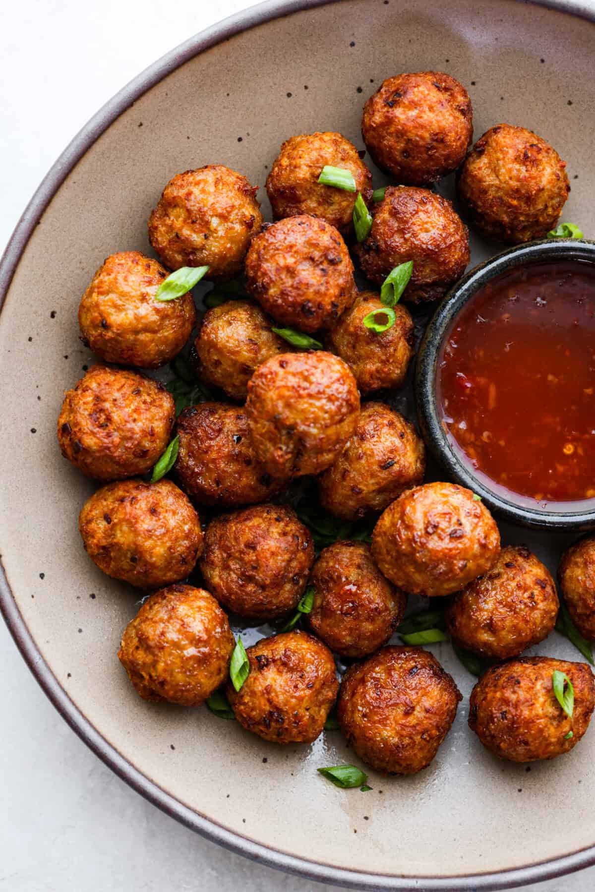 Top view of  bola bola filipino meatballs in a bowl with a side of dipping sauce.