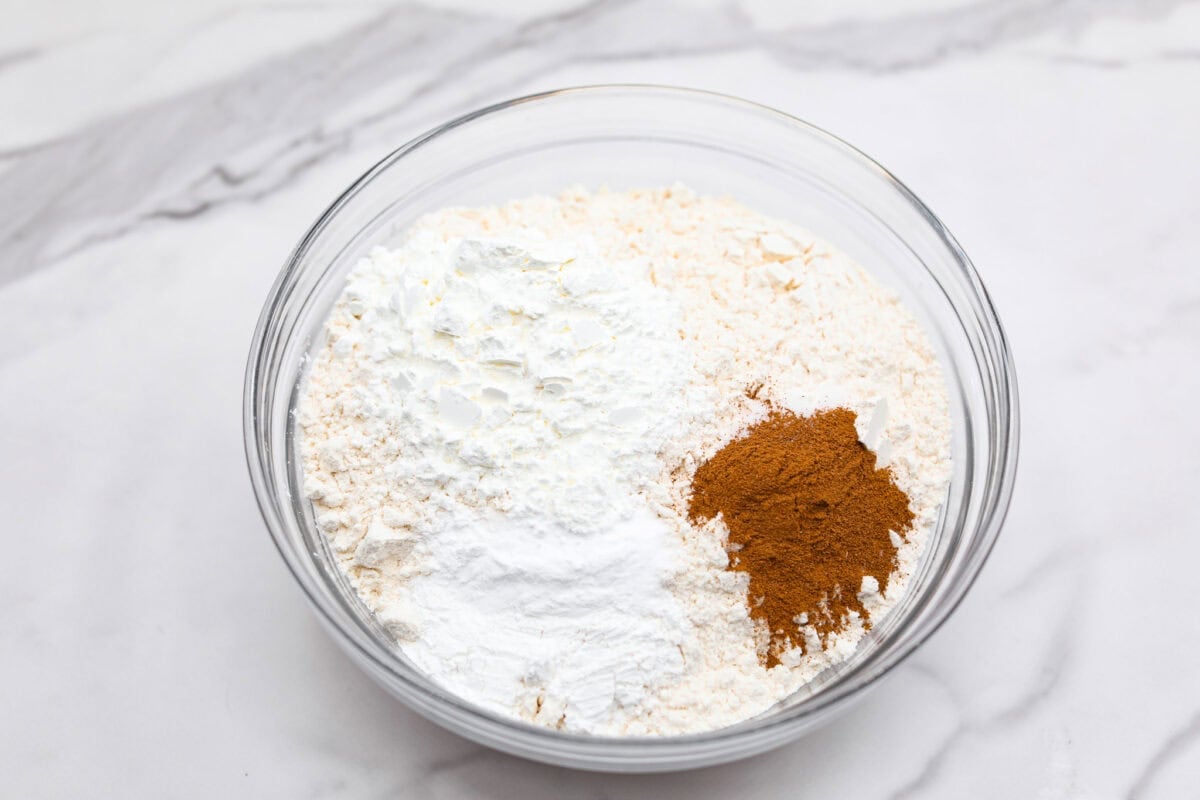 Overhead shot of flour, cornstarch, baking powder, baking soda, cinnamon and salt in a bowl. 