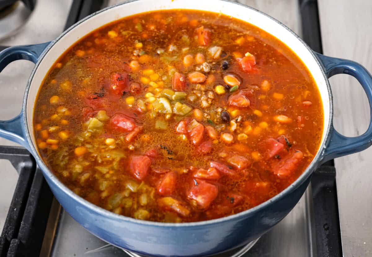 Angle shot of beef mixture with all of the canned vegetables and beef broth added to it. 