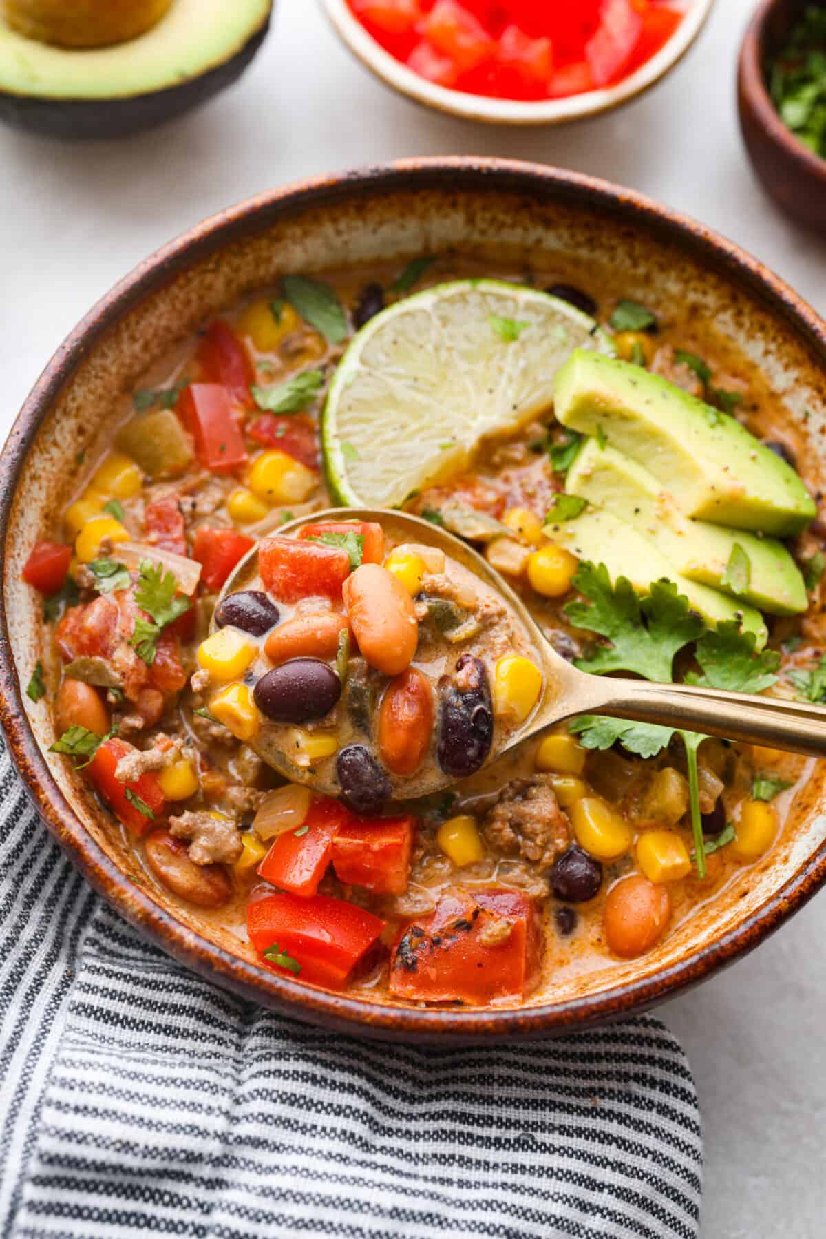 Overhead shot of a bowl of creamy taco soup with a golden spoon scooping out a bite. 