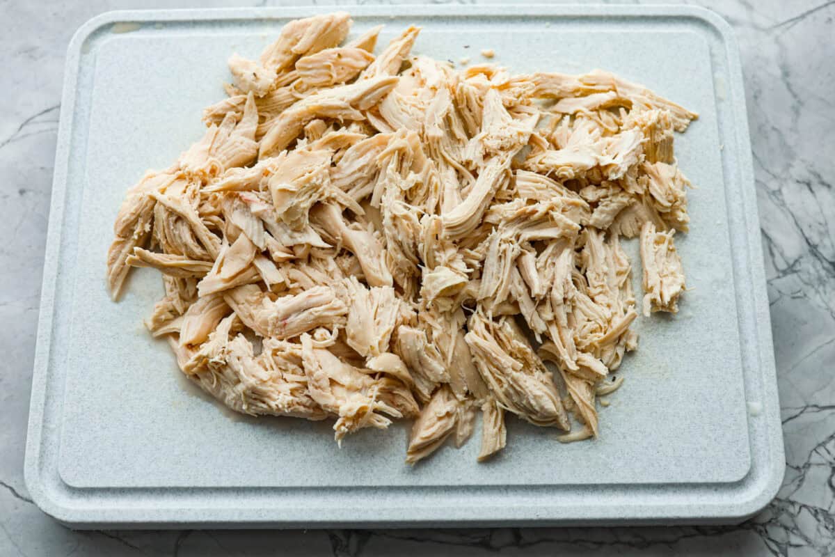 Overhead shot shredded chicken on a cutting board. 