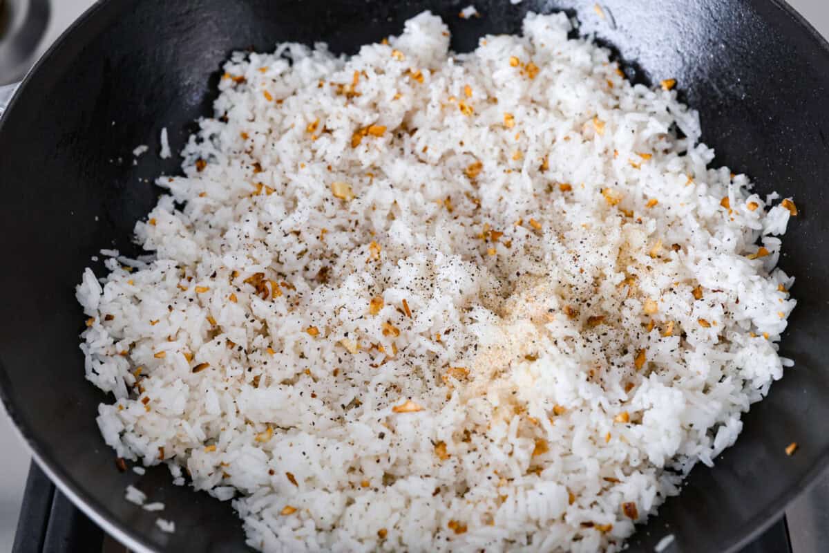 Overhead shot of seasonings added to the rice in the pan. 