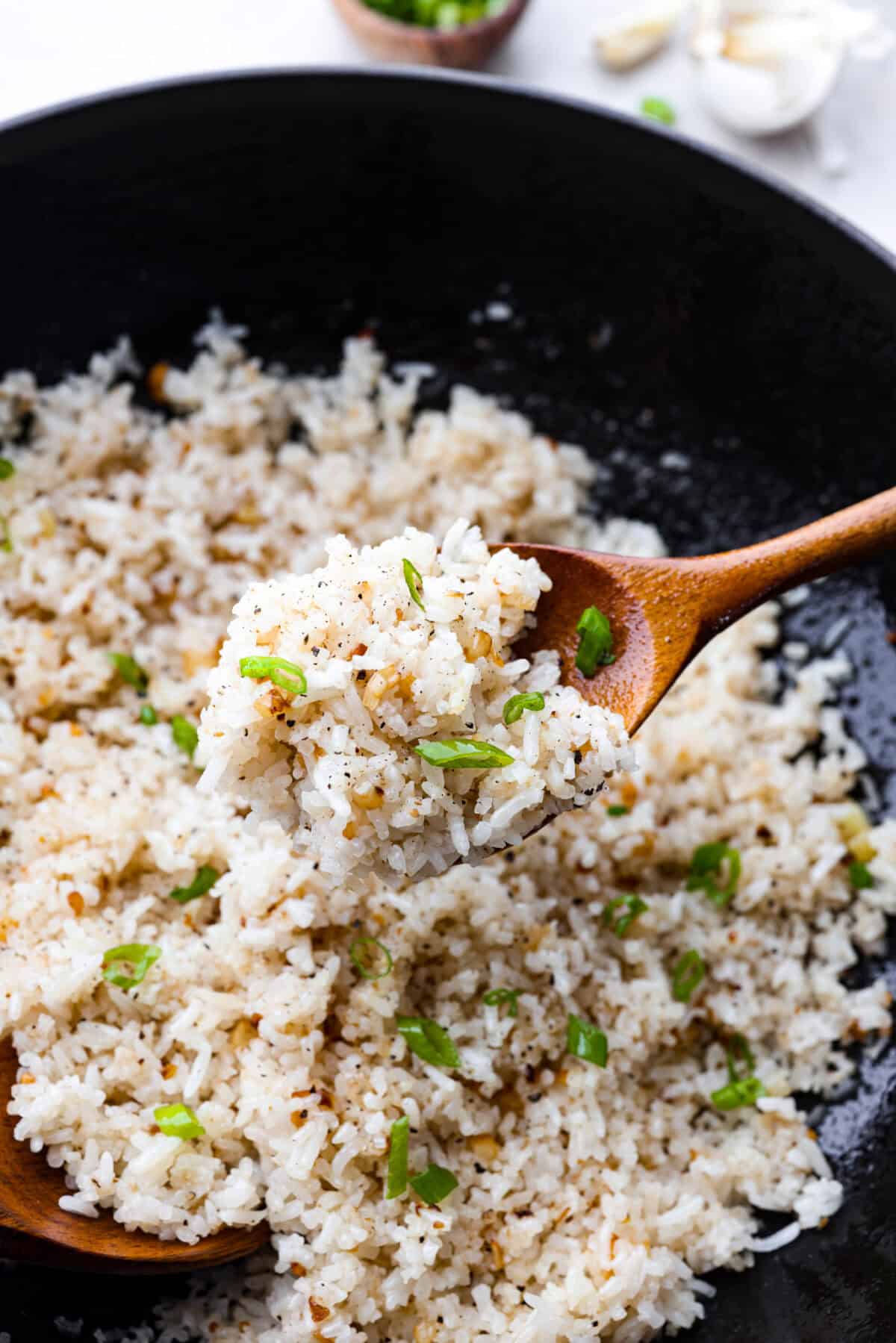 Close up shot of garlic fried rice on a wooden serving spoon. 