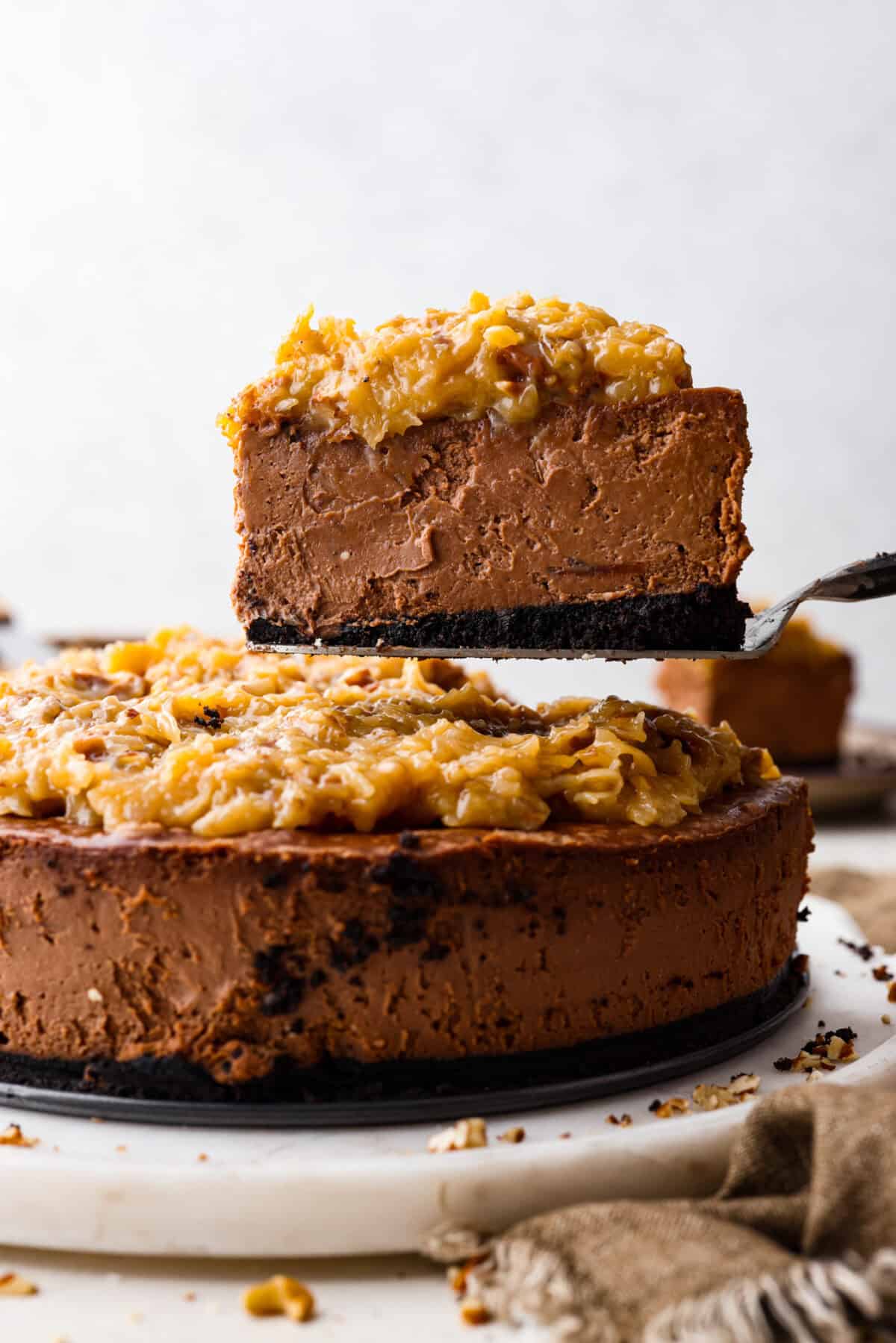 Close side view of a slice of German chocolate cheesecake on a serving spatula.