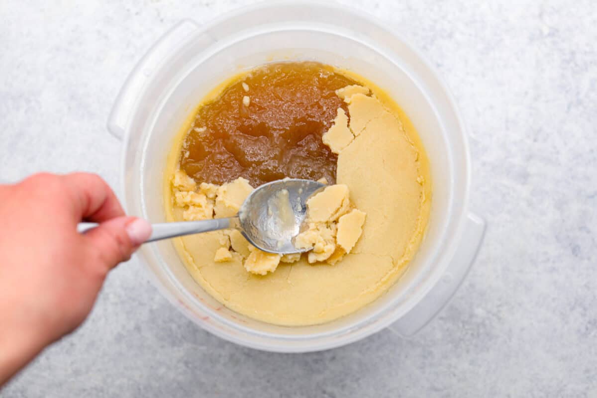 Overhead shot of someone scraping the solidified fat from the top of the broth. 