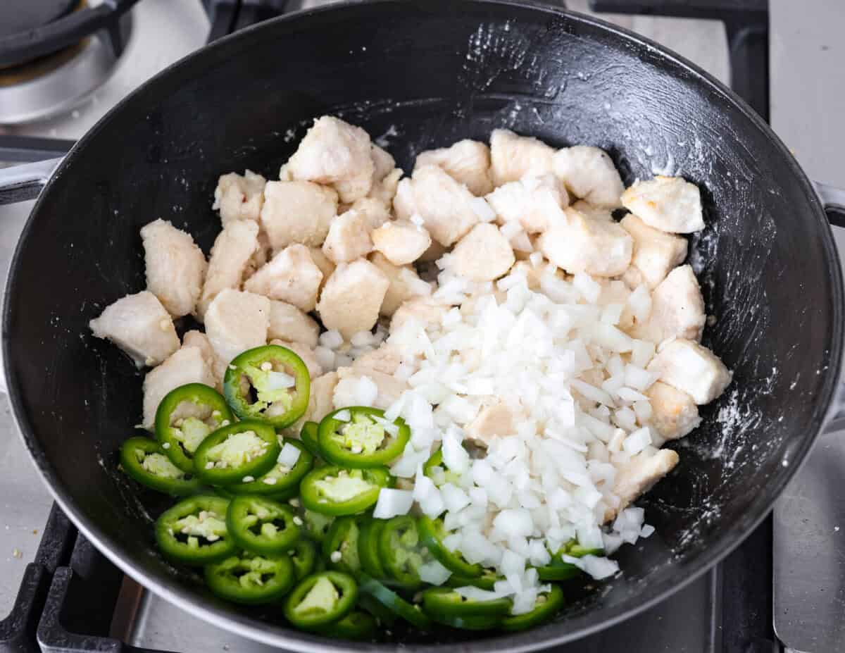 Angle shot of chicken jalapeños and onions in a skillet. 