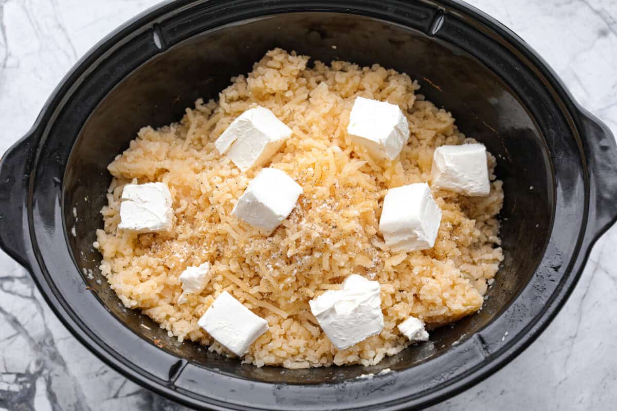 Overhead shot of mashed potatoes with cream cheese cubed over the top.