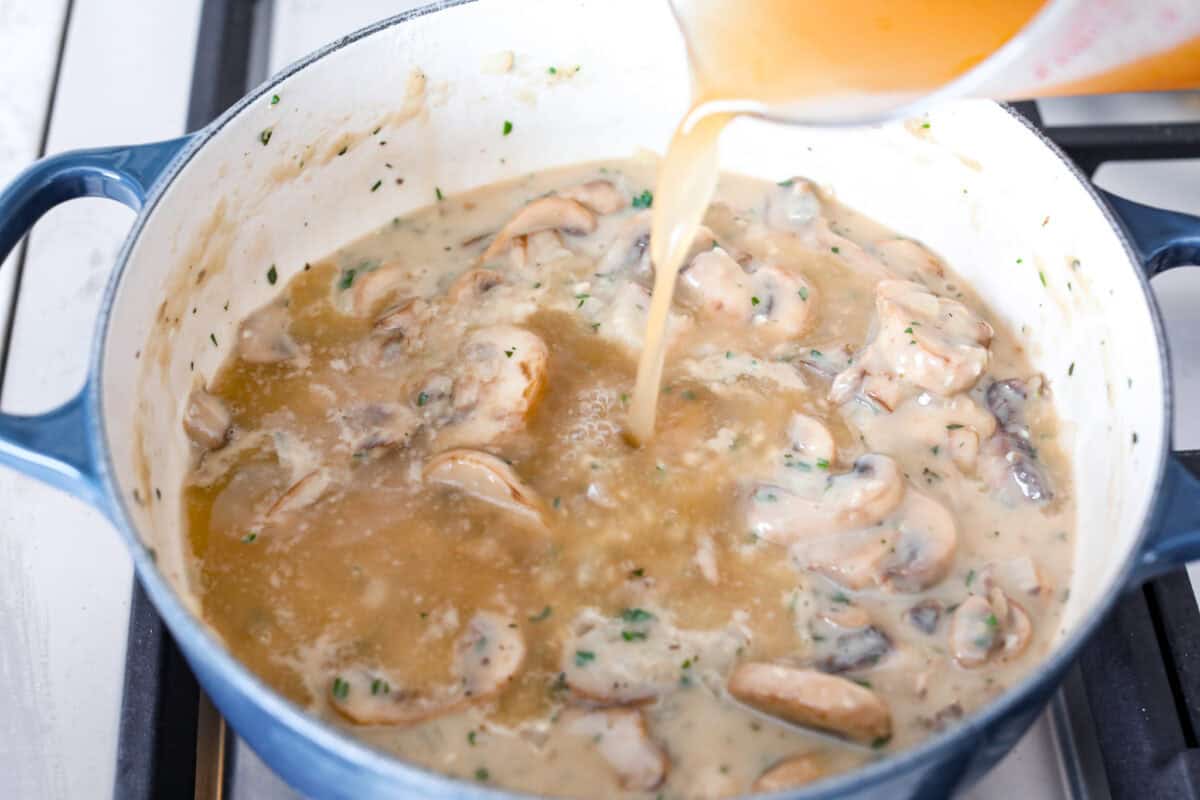 Angle shot of broth being poured into the mushroom and flour mixture. 