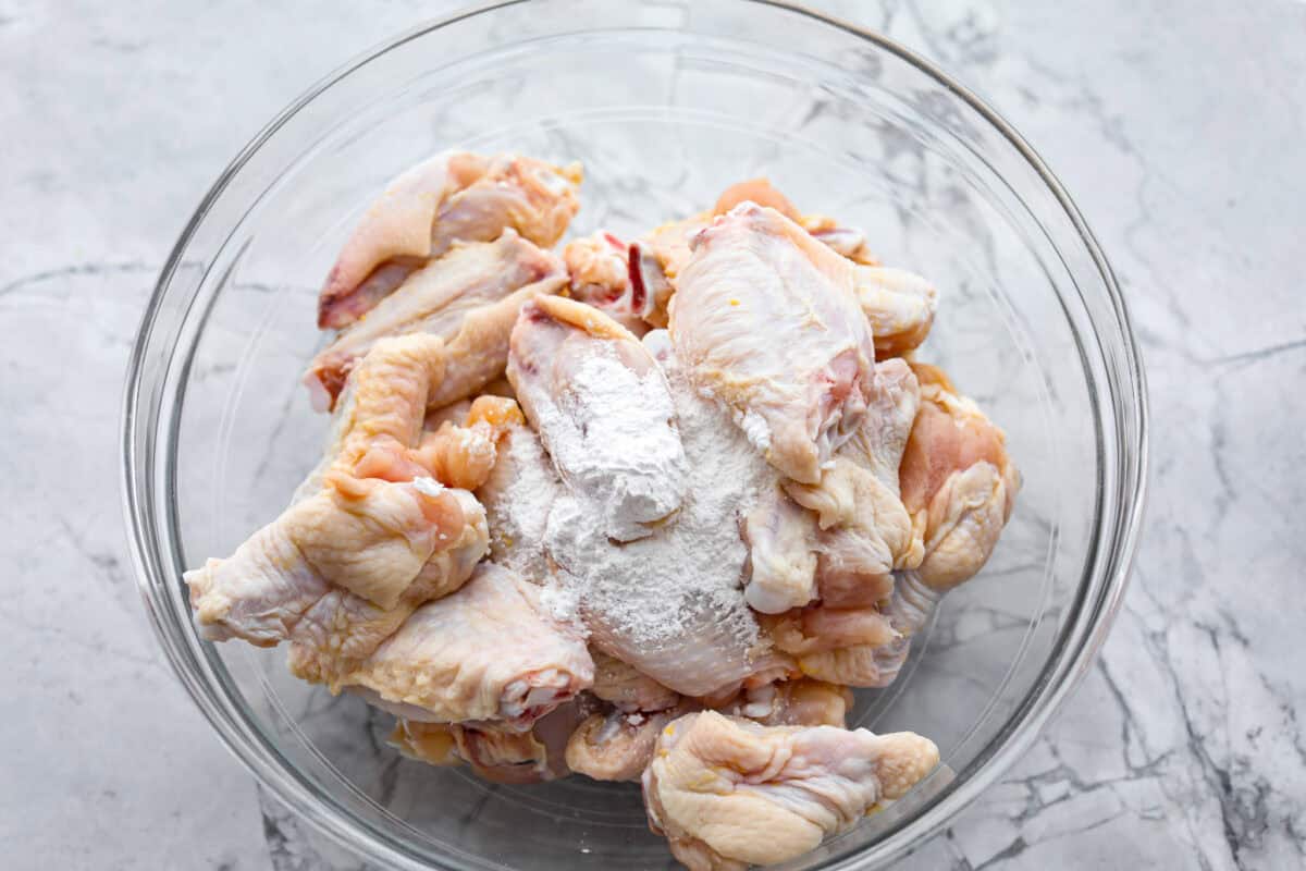 Overhead shot of raw wings with baking powder in a glass bowl.