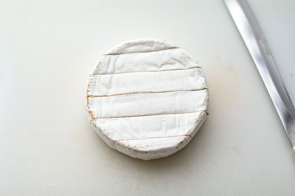 Overhead shot of a circle of brie cheese with horizontal slices through the top. 