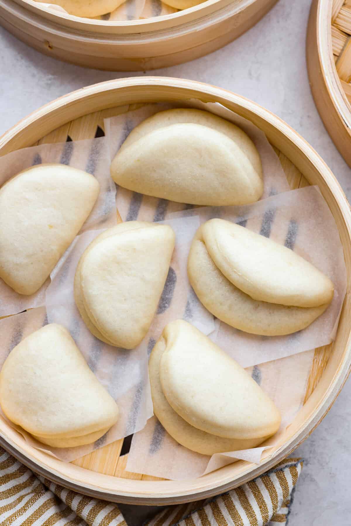 Overhead shot of cooked bao buns in a bamboo steamer. 