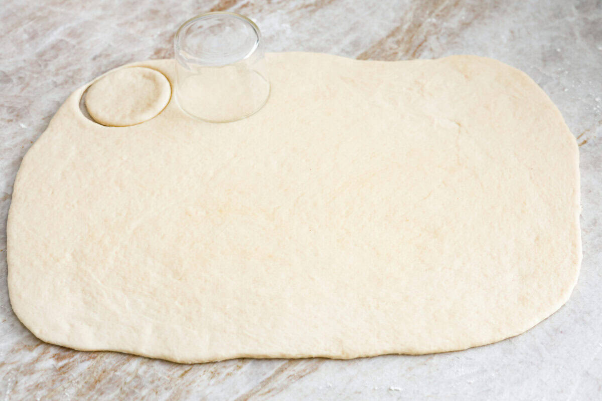 Angle shot of rolled out bao bun dough being cut into circles. 