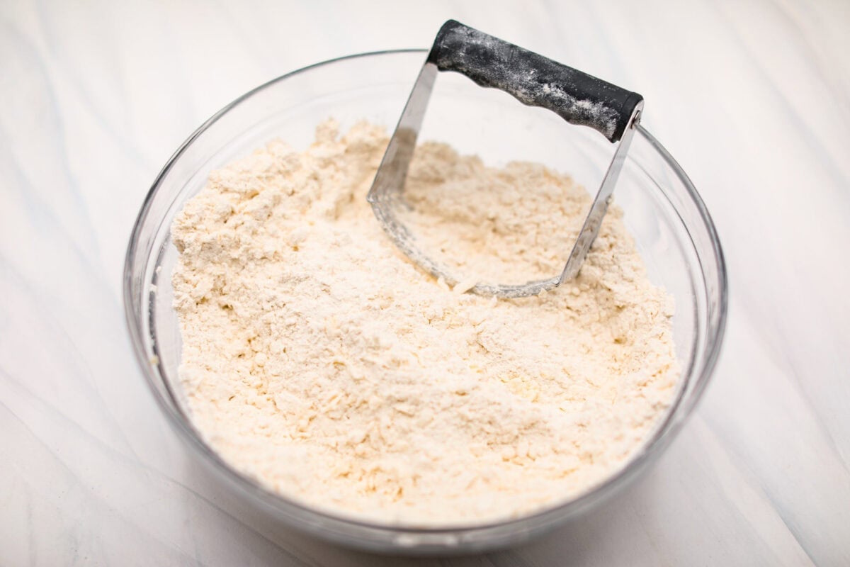 Angle shot of a pastry cutter in dry ingredients with shredded butter. 