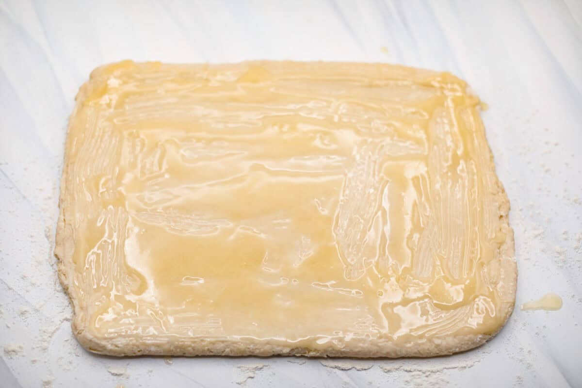 Overhead shot of melted butter spread on the rolled out dough. 