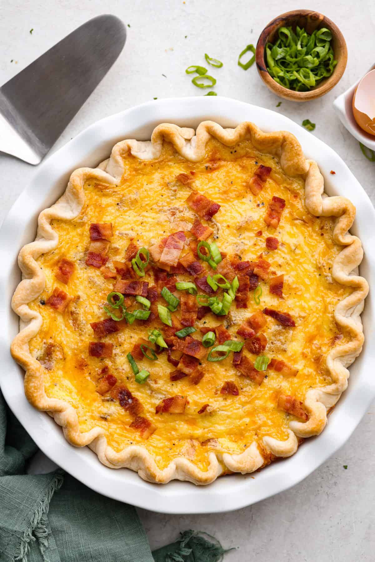 Overhead shot of baked cowboy quiche with green onion and bacon bits as garnish on the top.