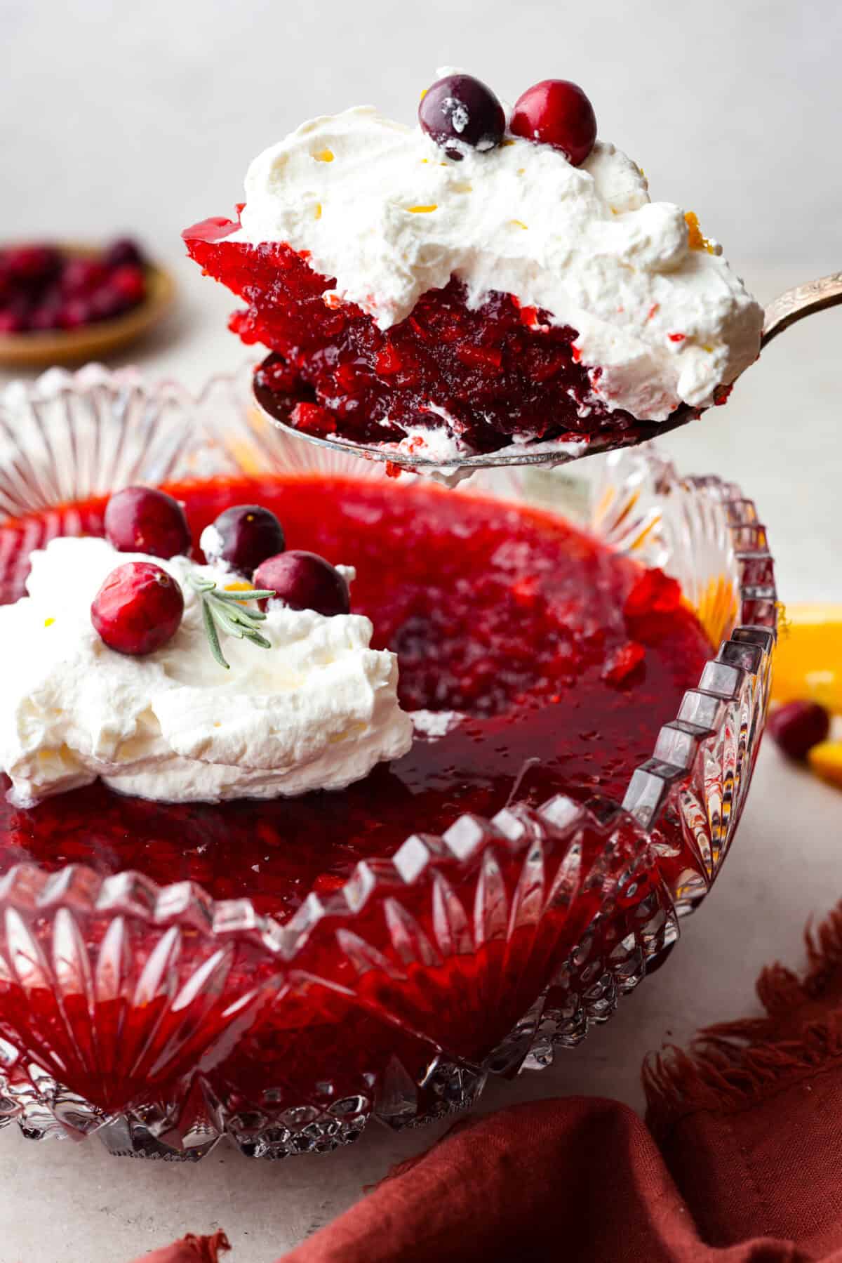 Side shot of a scoop of cranberry jello salad being lifted out of the serving bowl.