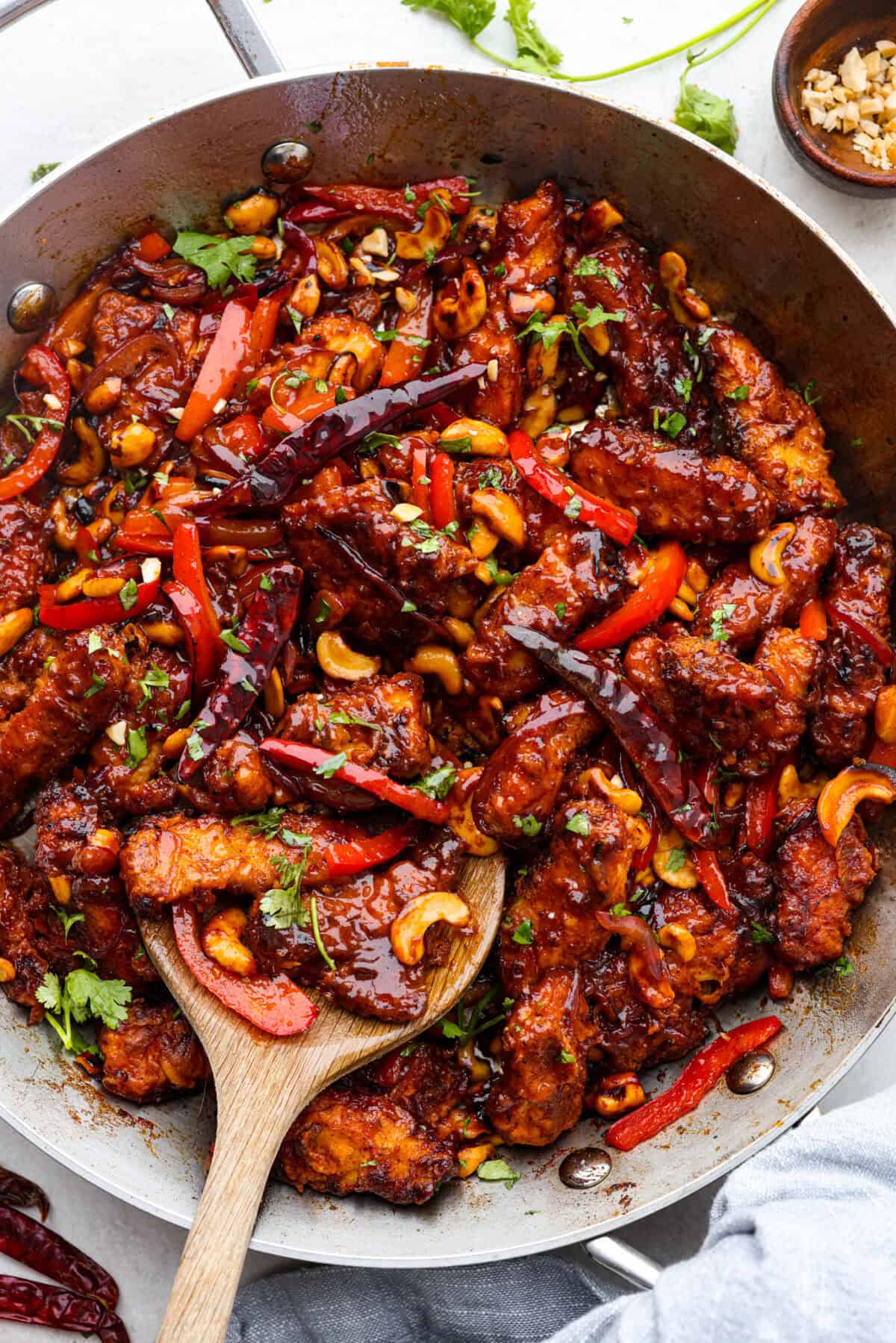 Overhead shot of dragon chicken in a wok with a wooden spoon. 