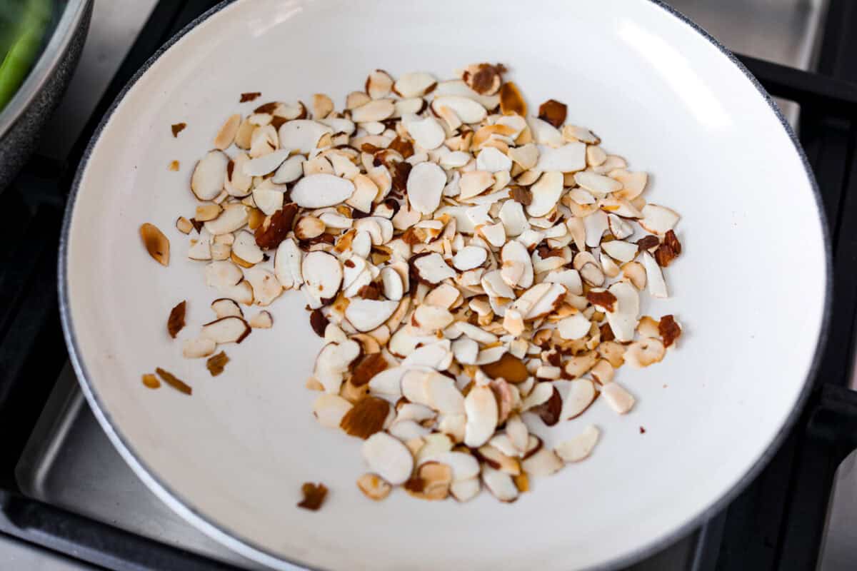 Overhead shot of almonds toasting in a skillet. 