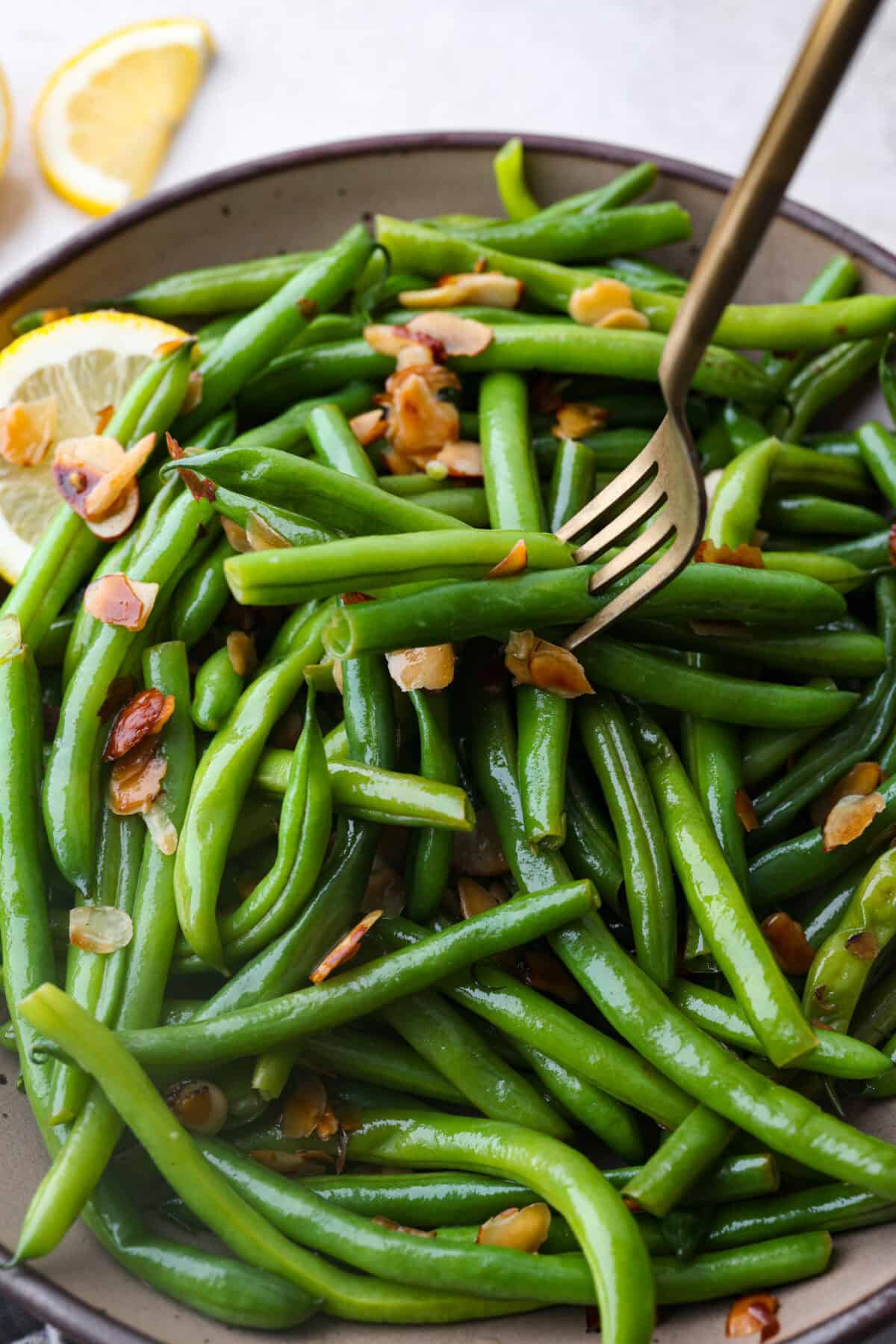 Angle shot of green beans Almondine with a fork spearing some of the beans. 