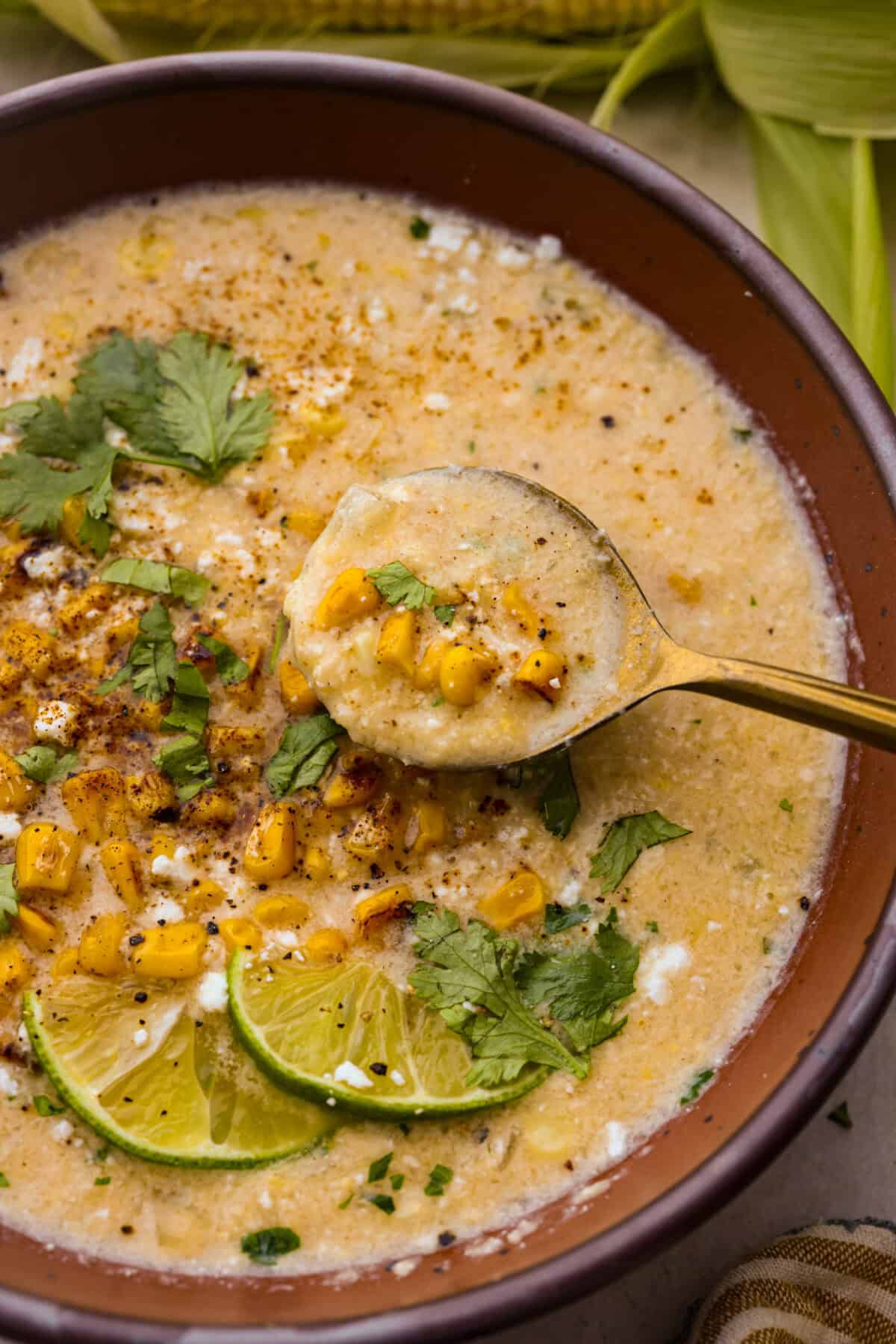 Close up shot of Mexican street corn in a bowl with a spoon. 