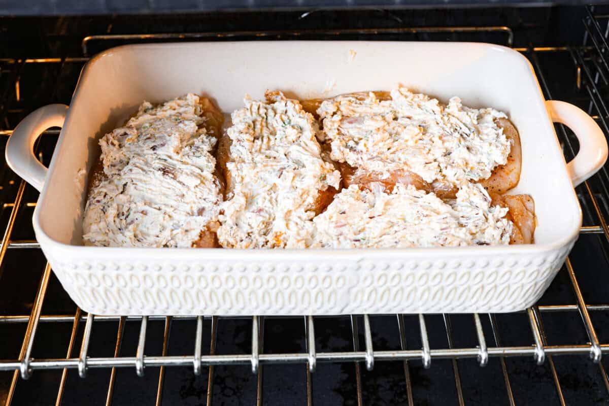 Angle shot of topped chicken breasts in baking dish in the oven. 