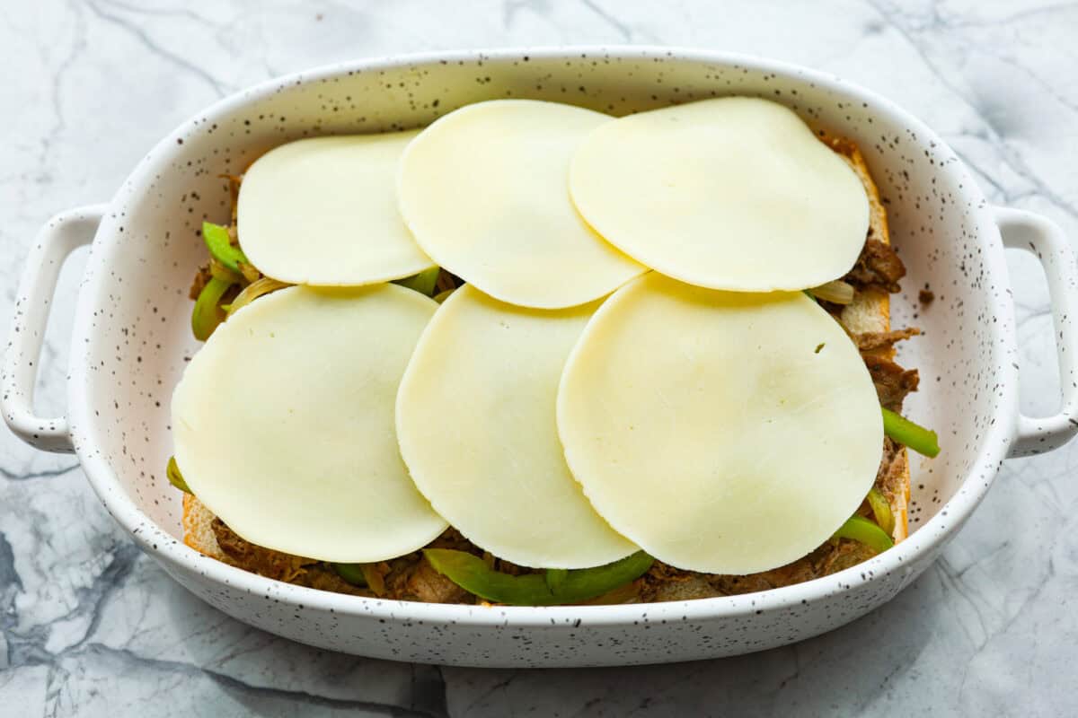 Overhead shot of slices of provolone over the veggies and beef. 