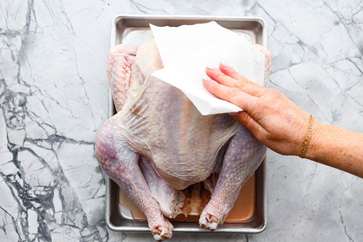 Third photo of a paper towel patting the turkey dry.